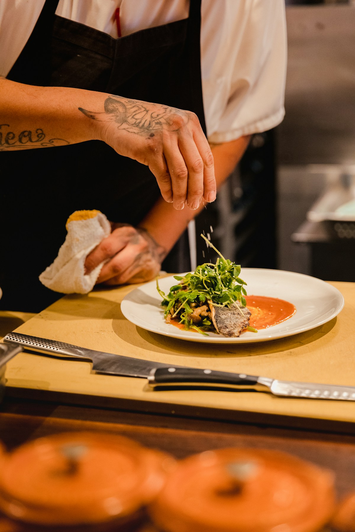 A chef carefully finishing a plated dish in a restaurant kitchen